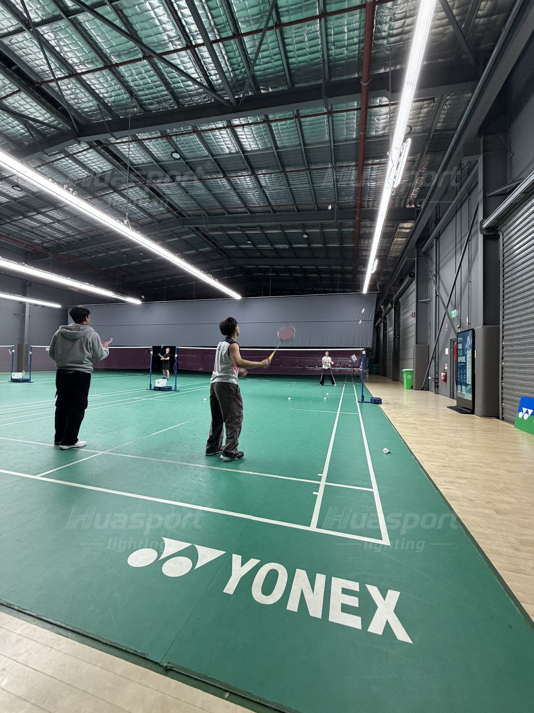 Australian badminton court seen from court level with the fixture row above the play