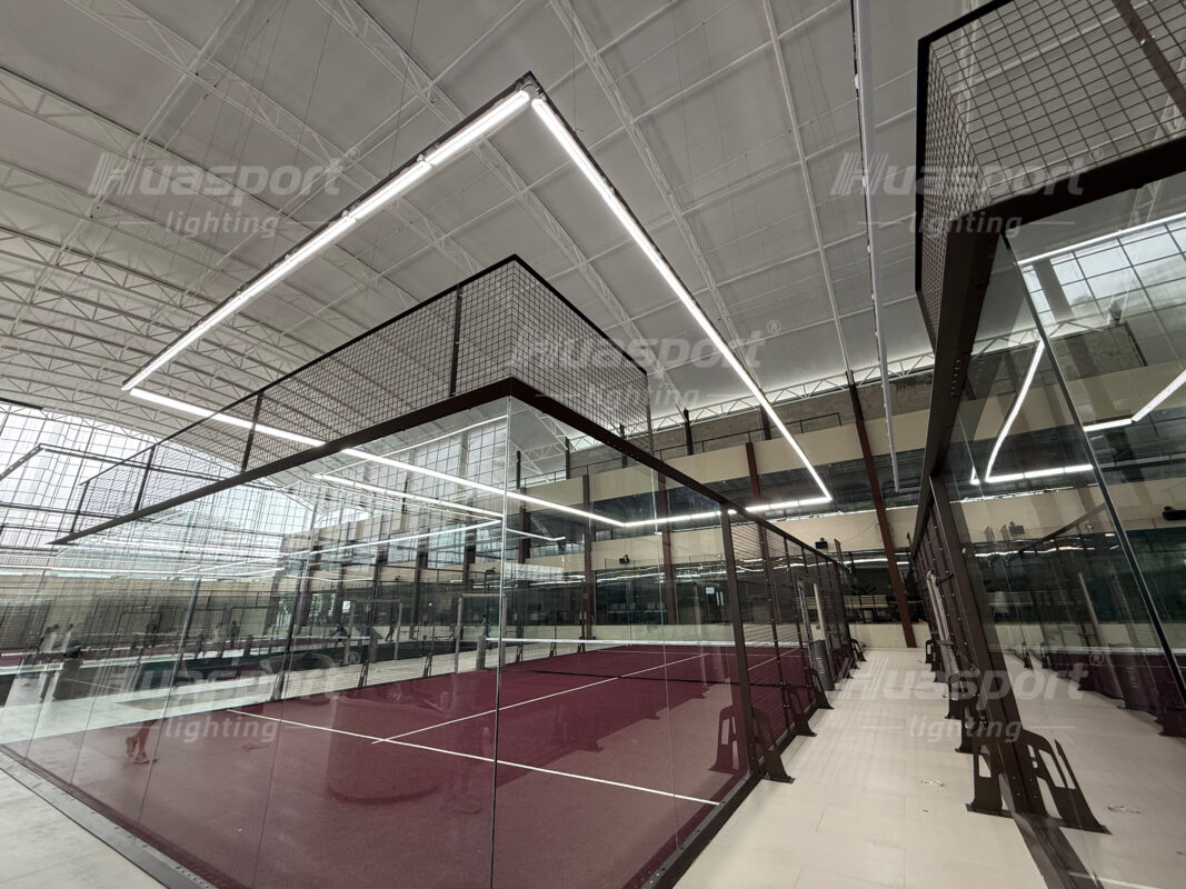 Indoor padel court lighting around glass walls using Huasport S70 long-bar anti-glare fixtures