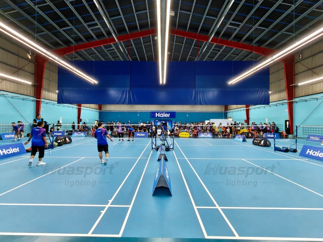 Malaysia badminton court lighting with active players and Huasport S70 42W long-bar fixture rows