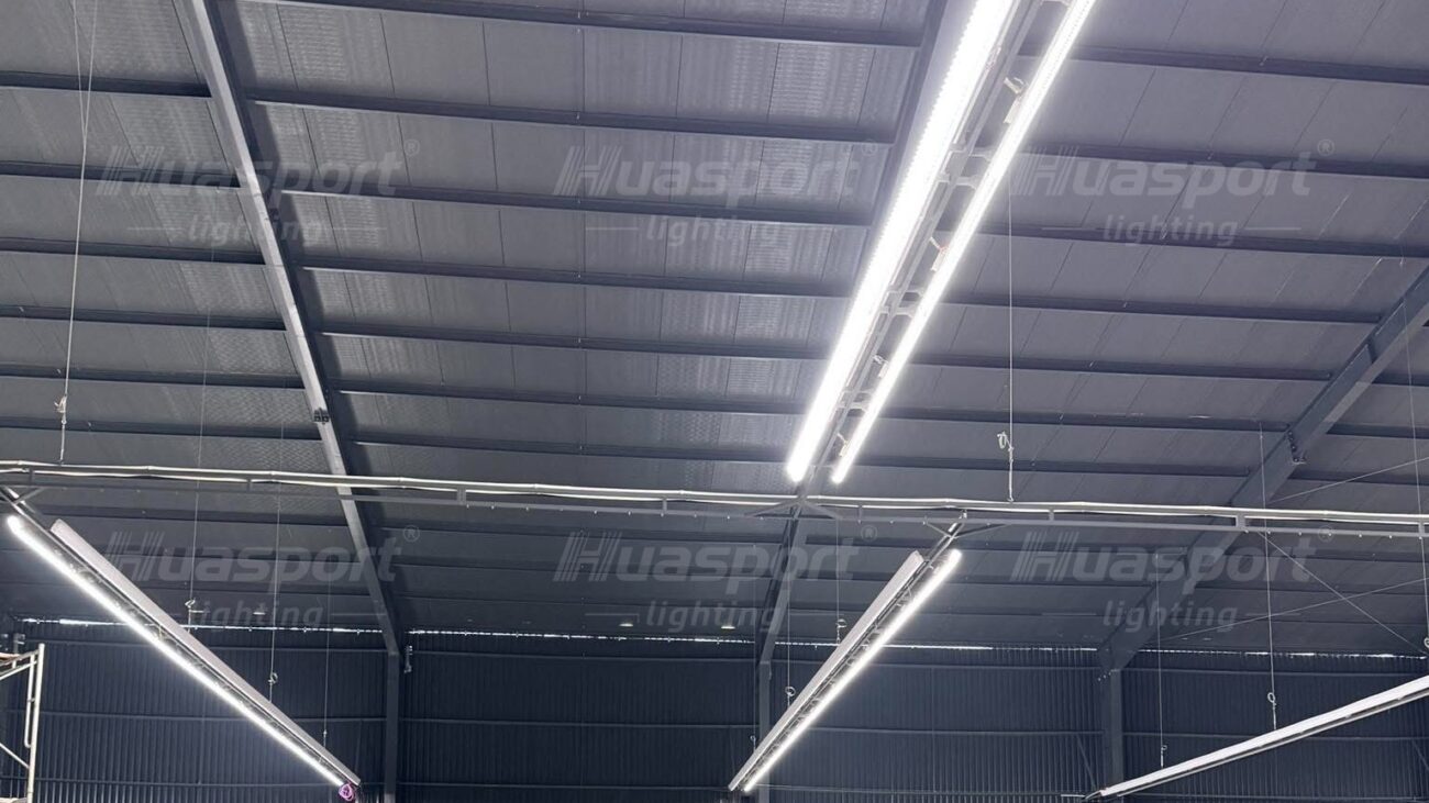 Long-bar lighting rows suspended below dark steel roof beams in a Vietnam hall