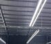 Long-bar lighting rows suspended below dark steel roof beams in a Vietnam hall